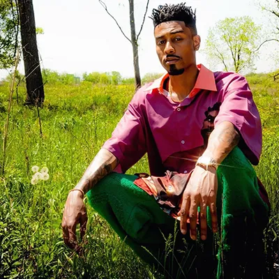 Sir Michael Rocks kneeling in a field of grass.